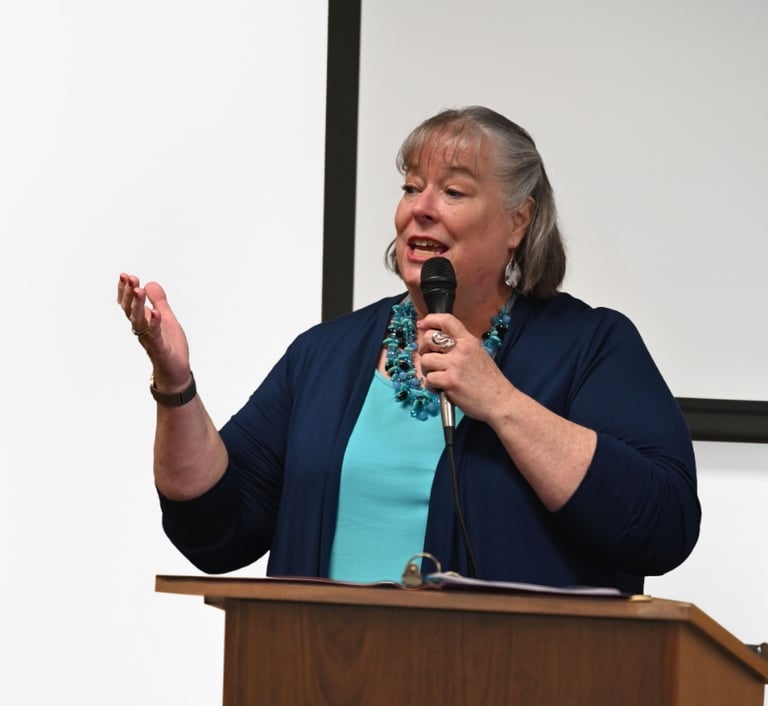 Debbie Chen speaking on stage with a microphone, Business Leadership Coach and speaker.