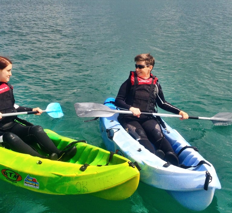 Two kayakers side by side with deep green sea