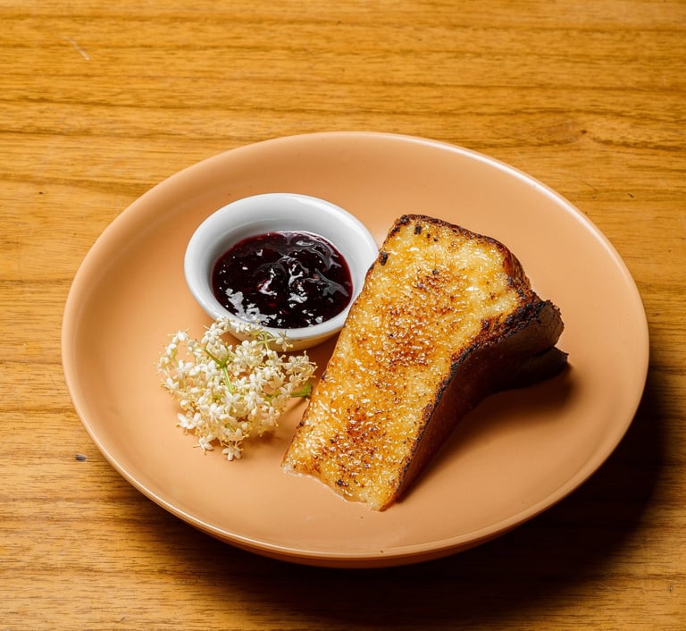 a plate of a slice of cheesecake and a bowl of jam