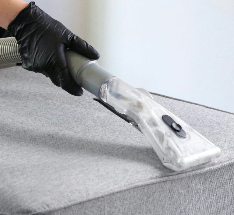 Technician using an extraction tool on a grey upholstered surface.