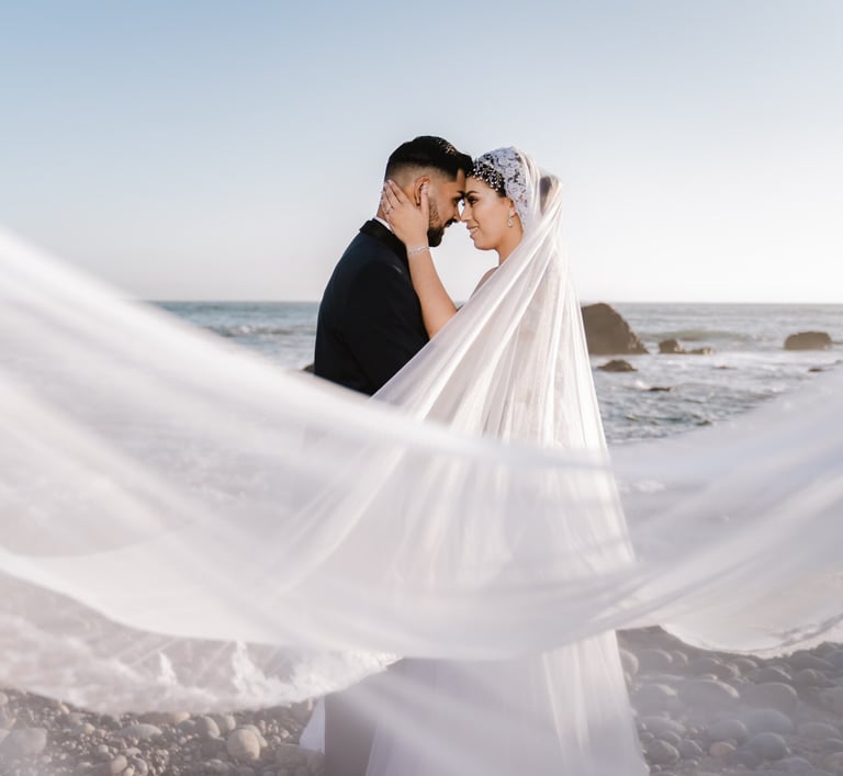 a bride and groom standing on a beach