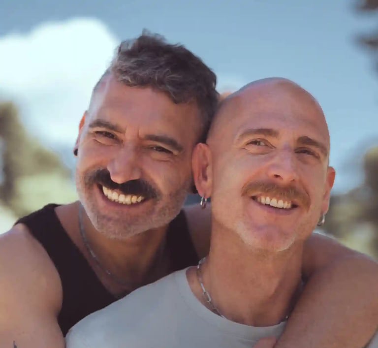 Dos hombres enamorados se abrazan felices frente a la cámara en una sesión fotográfica romántica LGBTQ+