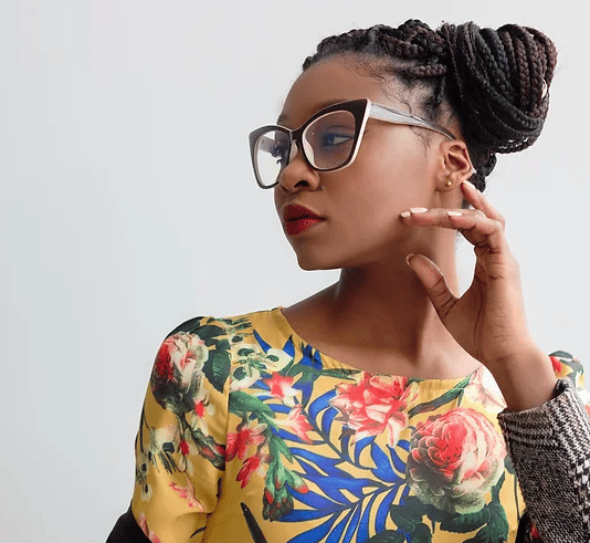 African-American woman with floral print top and hair pulled in a braided bun