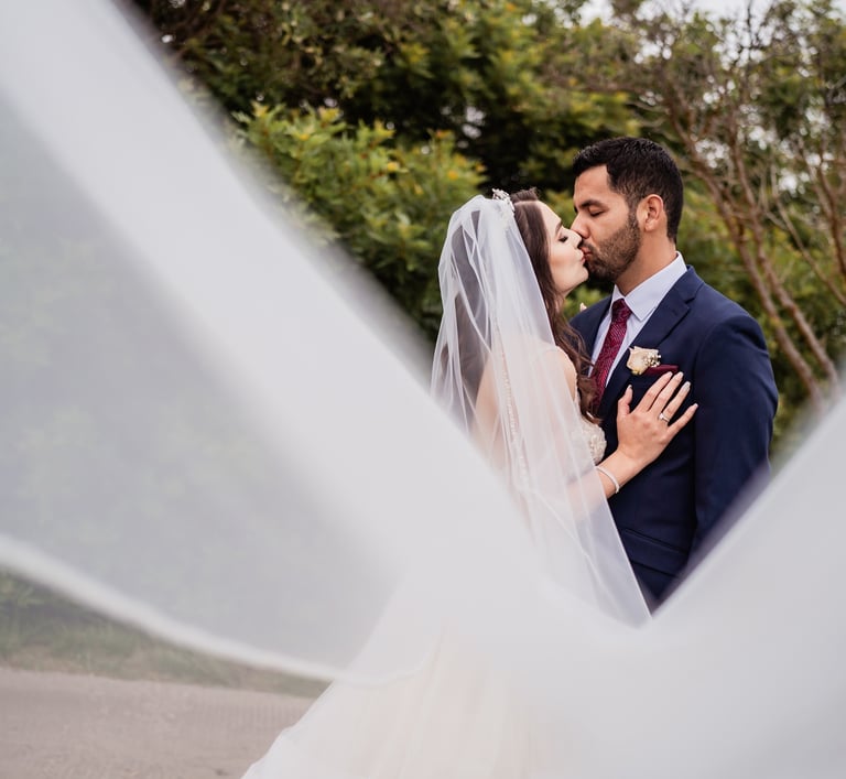 a bride and groom kissing in a veiled veil