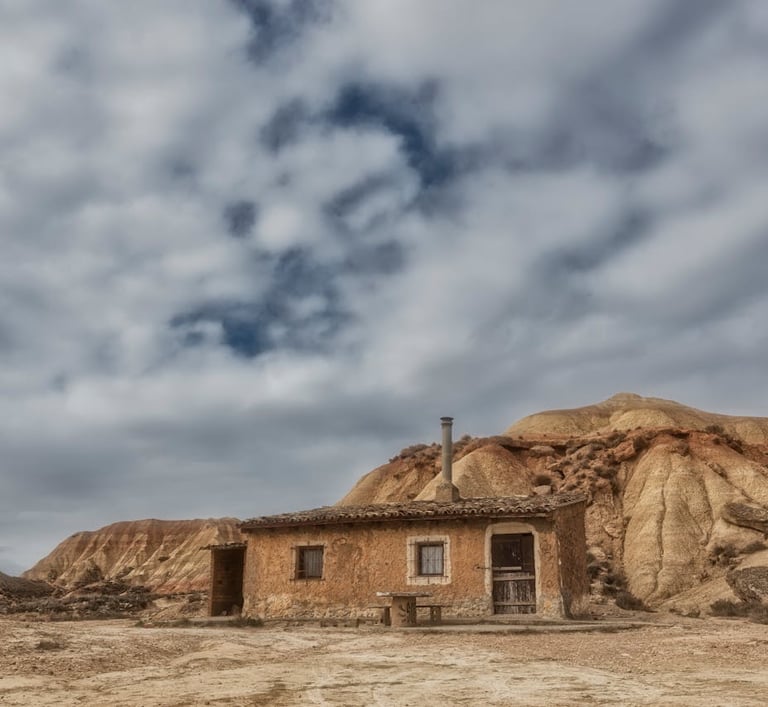 Antigua cabaña de piedra solitaria junto a cerros erosionados en el paisaje desértico de Bardenas