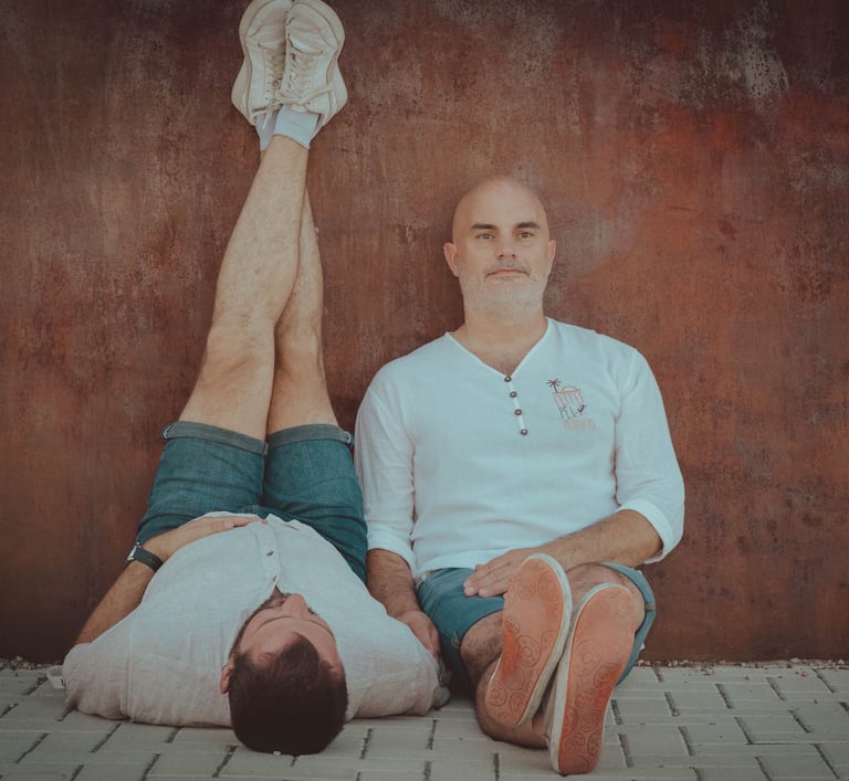 "Pareja gay de novios sentados en verano, disfrutando del ambiente del Pride y celebrando su amor."