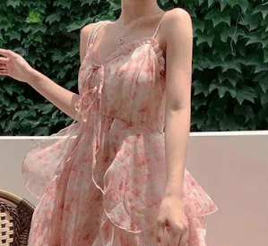 A woman wearing a light, flowy dress with small pink flowers and many large flowy layers.