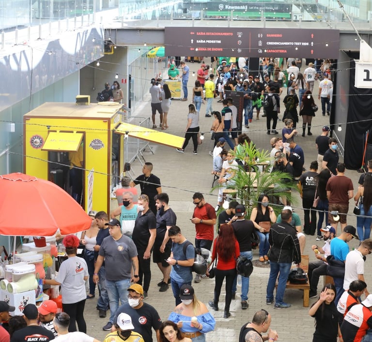 Pessoal caminhando no evento e outros pedindo comida no food truck