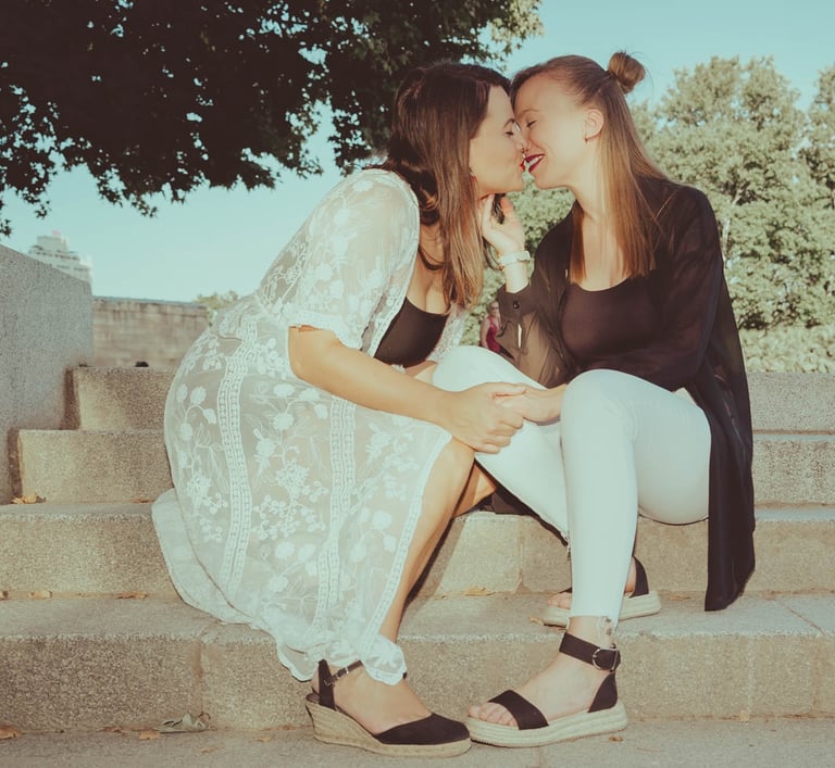 "Pareja lesbiana besándose en Madrid durante el Gay Pride en verano, celebrando su amor y la diversidad LGBTQ+."