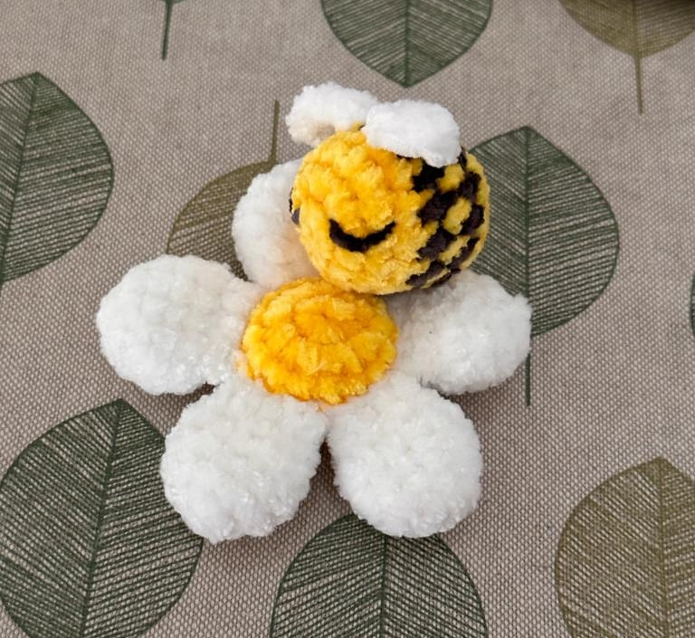 a handmade amigurumi stuffed daisy with bee toy 