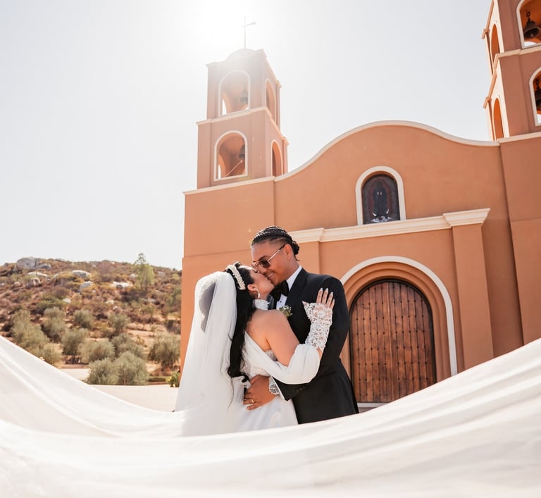 a bride and groom kissing in front of a church