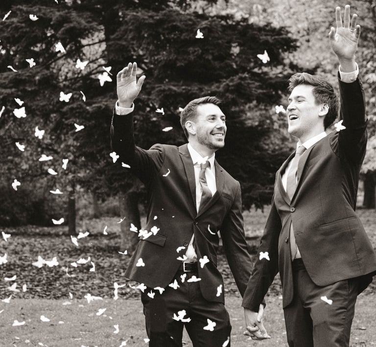 Pareja de recién casados gays sonriendo y lanzando pétalos de rosa mientras se toman de la mano. Gay wedding celebration.