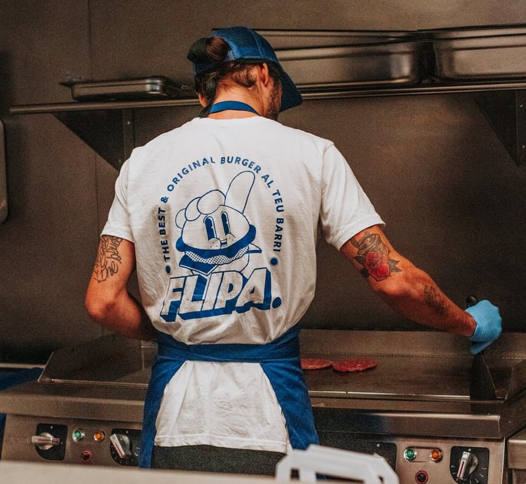 Cocinero de Flipa cocinando carne en la plancha con camiseta oficial de la marca