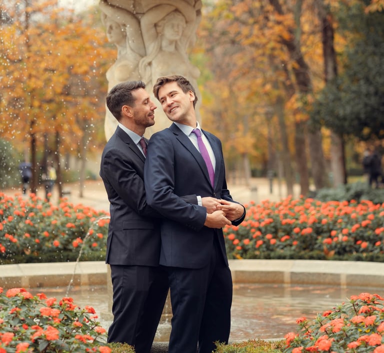 Pareja de recién casados gays frente a una fuente, abrazándose con amor. Gay marriage Spain.
