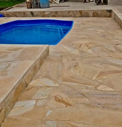 Pedra são tomé caco amarelo antiderrapante assentado no chão ao redor da piscina área externa