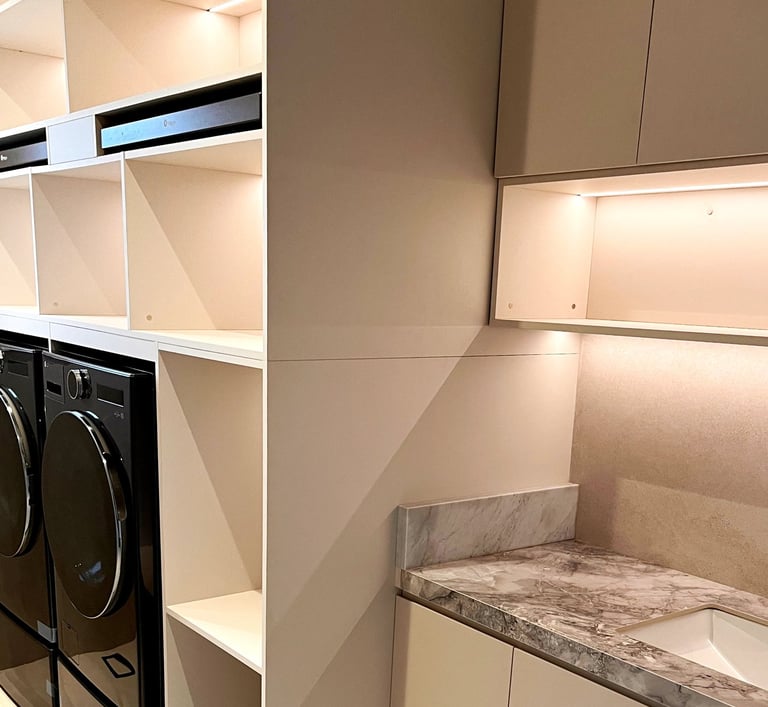 Modern laundry room with black front-load appliances, marble countertops, and built-in white storage cabinets.