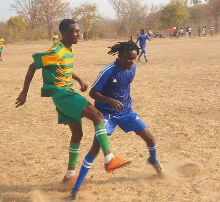 Soccer players in action on dusty field 