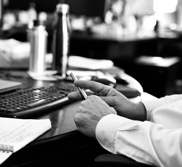 Mains d'un employé tenant un stylo devant l'ordinateur dans le bureau