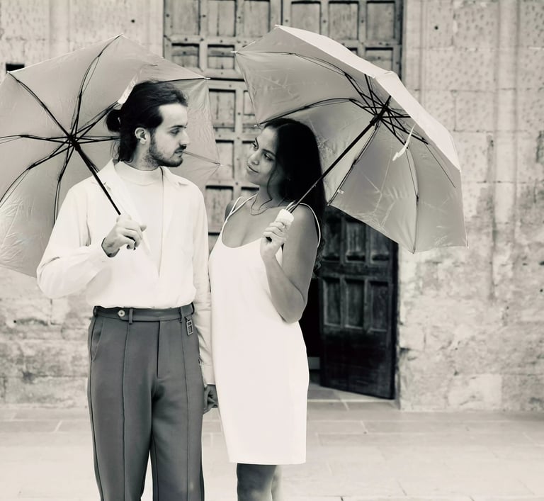 Séance d'un couple qui s'engage devant une église avec des parapluies