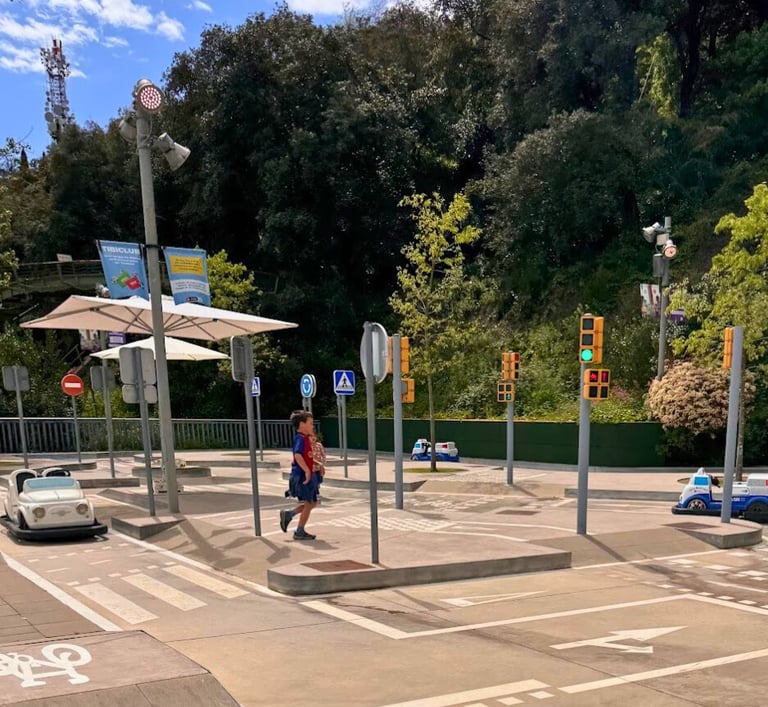 a young boy walking across a street with a car parked in front of him in the Tibidabo traffic park