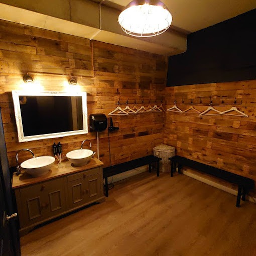 A male changing room from a private gym facility in east London. There is a sink, mirror and benches