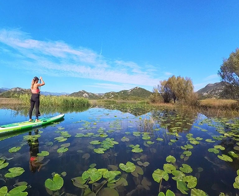girl on paddle board on lake skadar