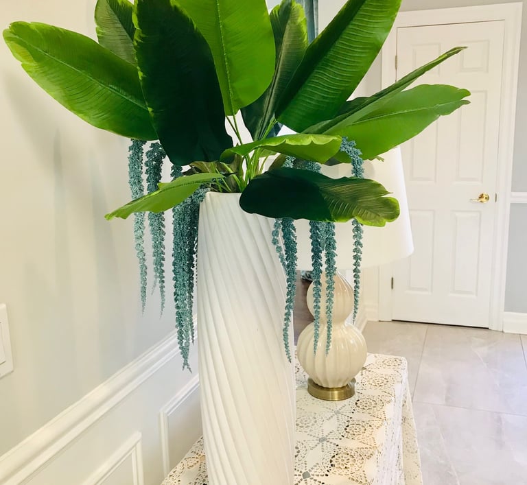 a big green plant and a table lamp in a foyer