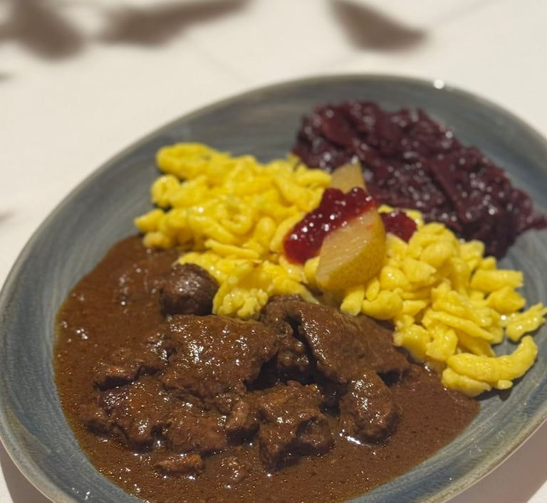 Rinderragout auf dem Teller mit Spätzle, Soße, Rotkraut