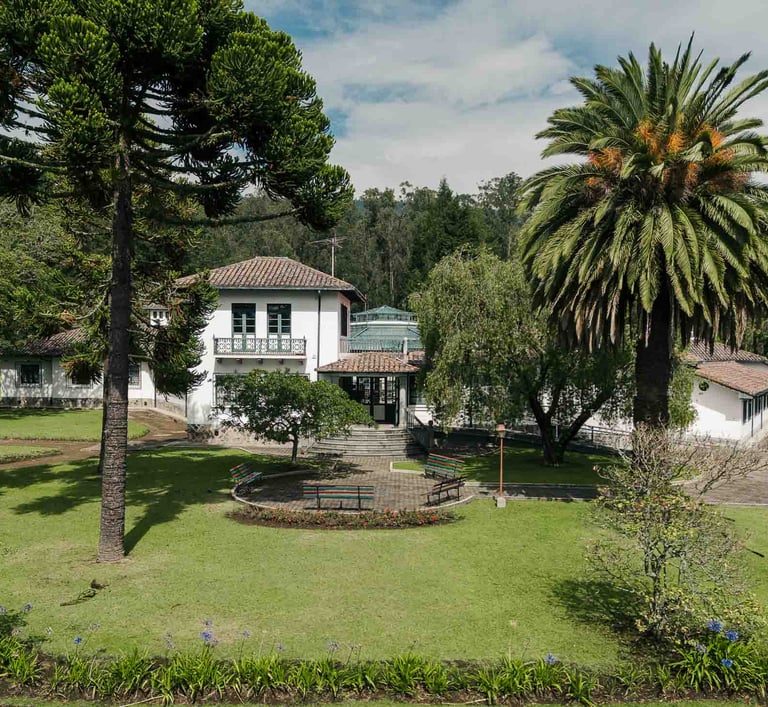 Fotografía con dron de mansión colonial de paredes blancas con techo naranja, cúpulas rodeada de naturaleza Quito Ecuador