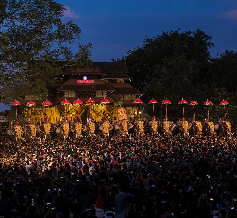 Thrissur Pooram festival celebration with illuminated parasols and a large crowd in front of a traditional temple.