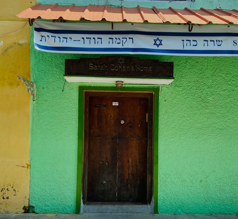 A green and yellow building with a door at Jew Street, Mattancherry Ernakulam 