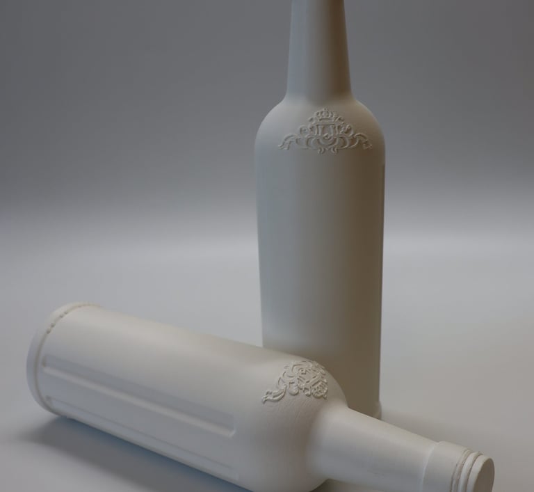 Du balti 3D spausdinti butelių prototipai iš PLA plastiko, stovintys ant balto pagrindo