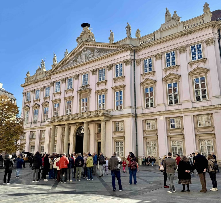 Fachada del Palacio Primacial de Bratislava en un día soleado, con un grupo de turistas reunidos en 