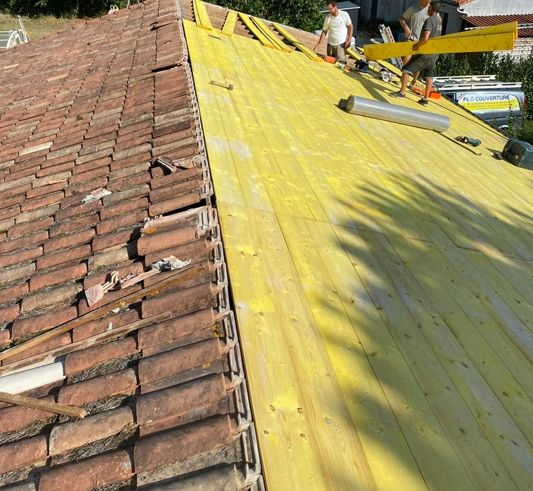 Des couvreurs professionnels installant de nouvelles planches de volige en bois et des tuiles en ter