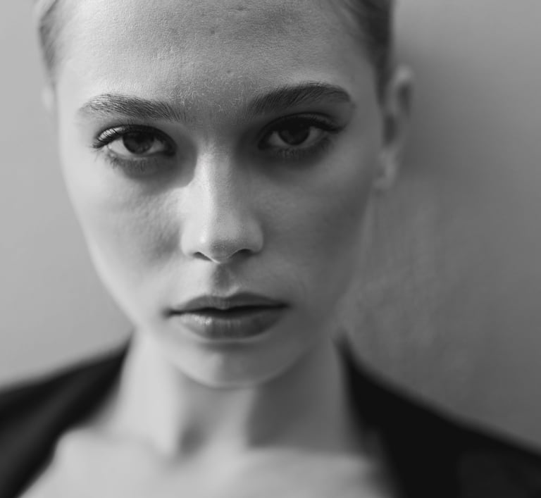Black and white close-up portrait of a woman with intense eyes and professional makeup.