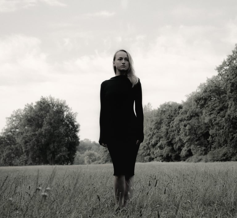 Portret kobiety na łące w tle drzewa, czerń i biel