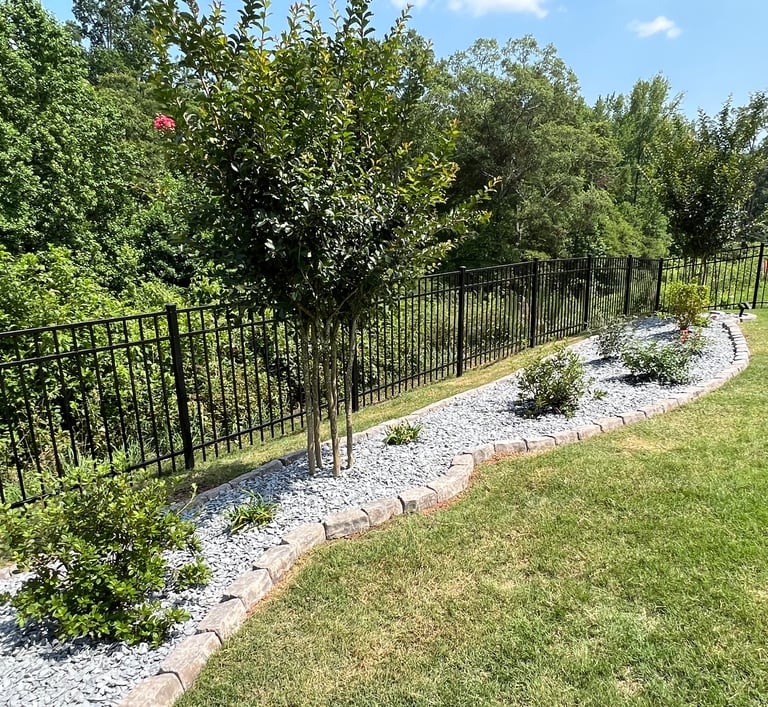 Created backyard flowerbed along the black fence with azaleas, butterfly bushes, roses, slate mulch and stone border.
