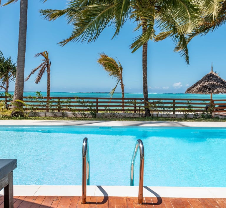 a pool with a lounge chair and palm and ocean view