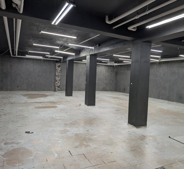 Large basement studio with a concrete floor and grey walls