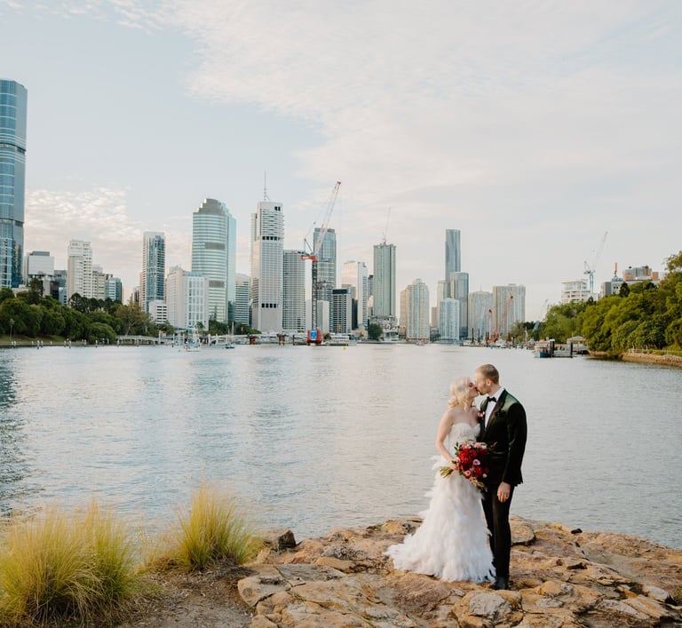 a bride and groom standing on a rock wall in Kangaroo Cliffs
