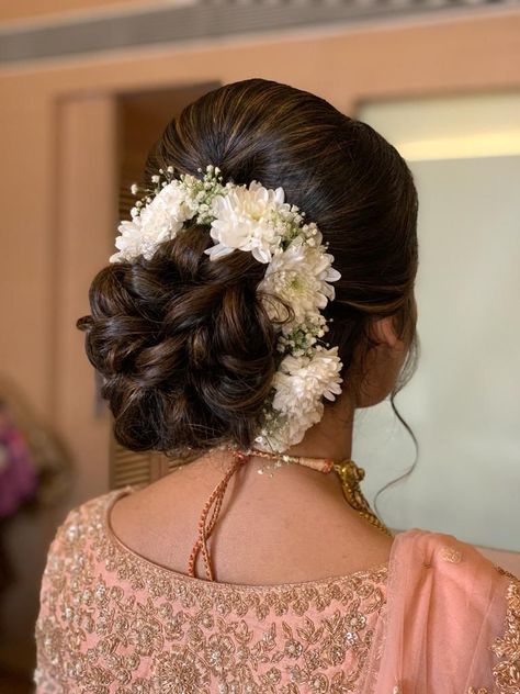 Elegant bridal bun decorated with white flowers for a wedding hairstyle