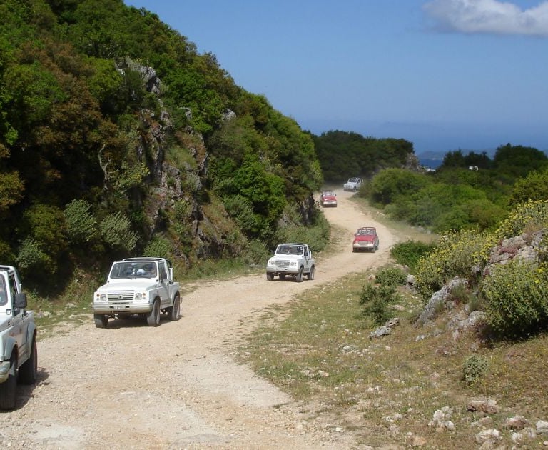 a group of cars driving down a dirt road