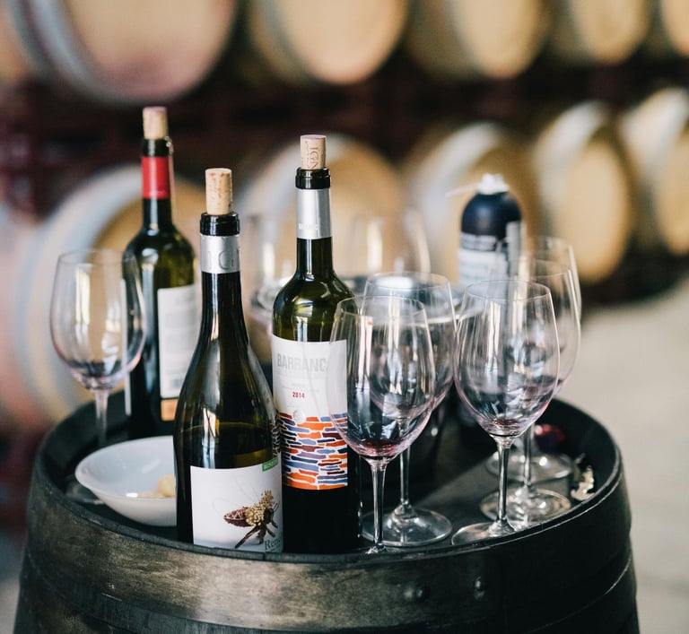 wine bottles and wine glasses on a barrel of wine