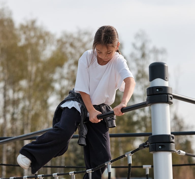 Fille grimpant sur une structure Kenguru Pro Kids Active Play en extérieur.