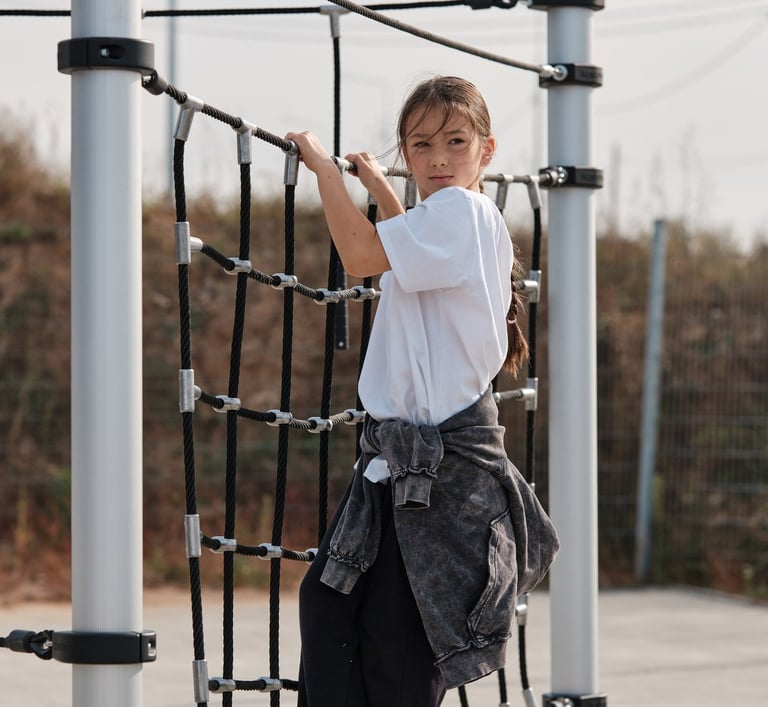 Fille grimpant sur une structure Kenguru Pro Kids Active Play en extérieur.