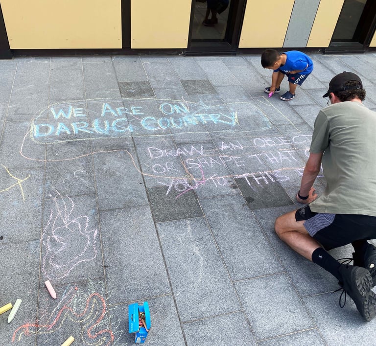 A child and an adult drawing on pavers with chalk.