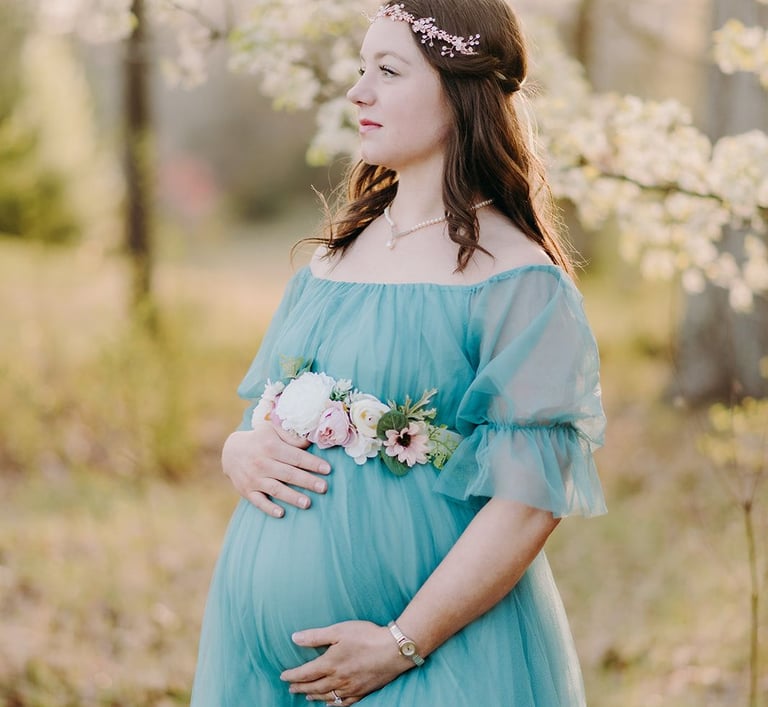 a pregnant woman in a blue dress standing in a field