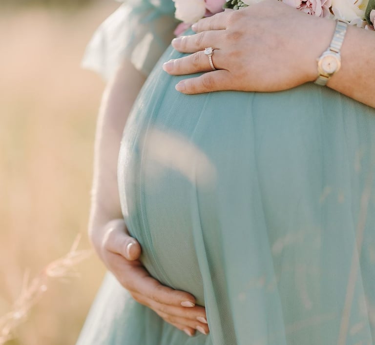 a pregnant woman in a blue dress with flowers on her belly