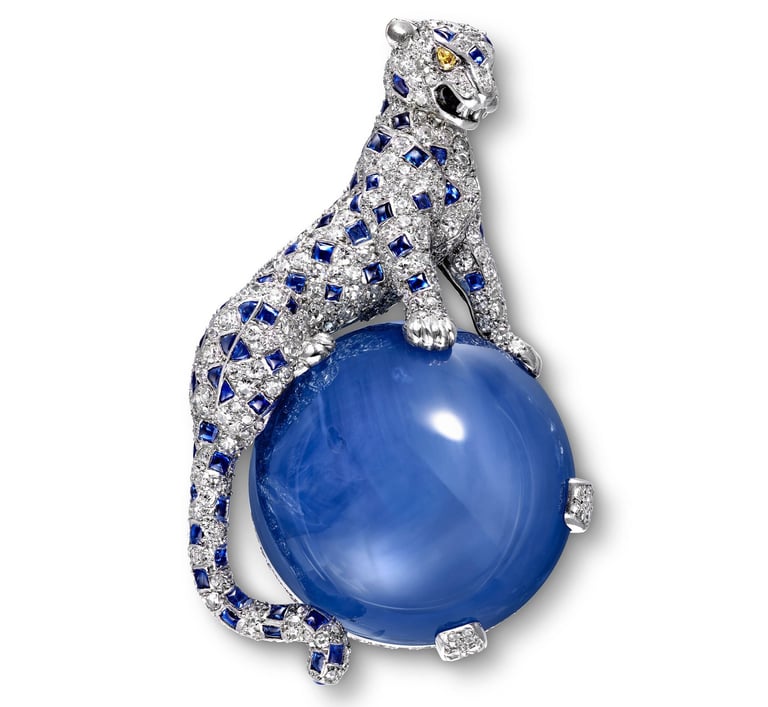 Cartier panther brooch with sapphires and diamonds perched on a blue sapphire cabochon.