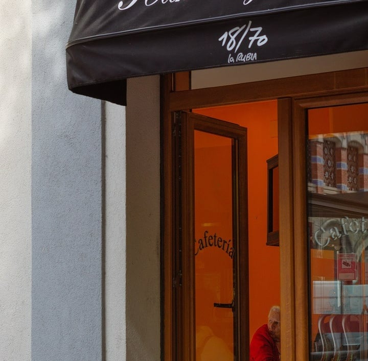 Fachada de una cafetería en la que se ve una persona dentro